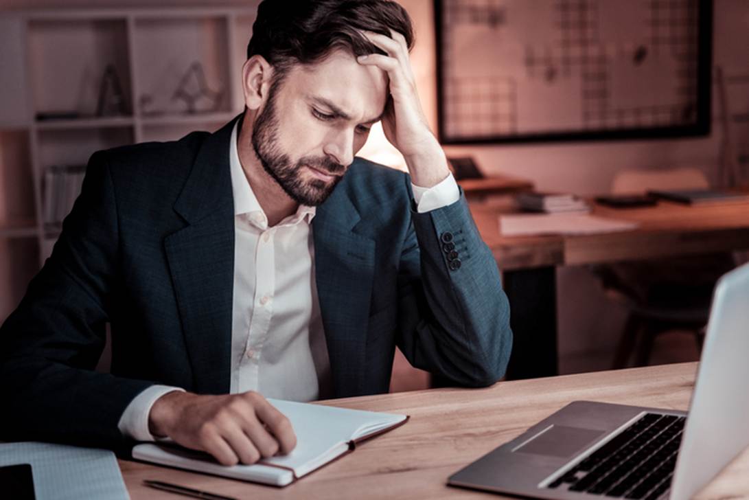 A person in a suit holding his head

AI-generated content may be incorrect.